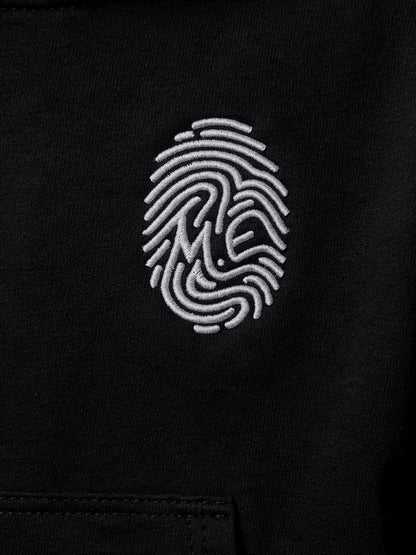 Détail de l’empreinte M.E blanche brodée — Hoodie Signature noir