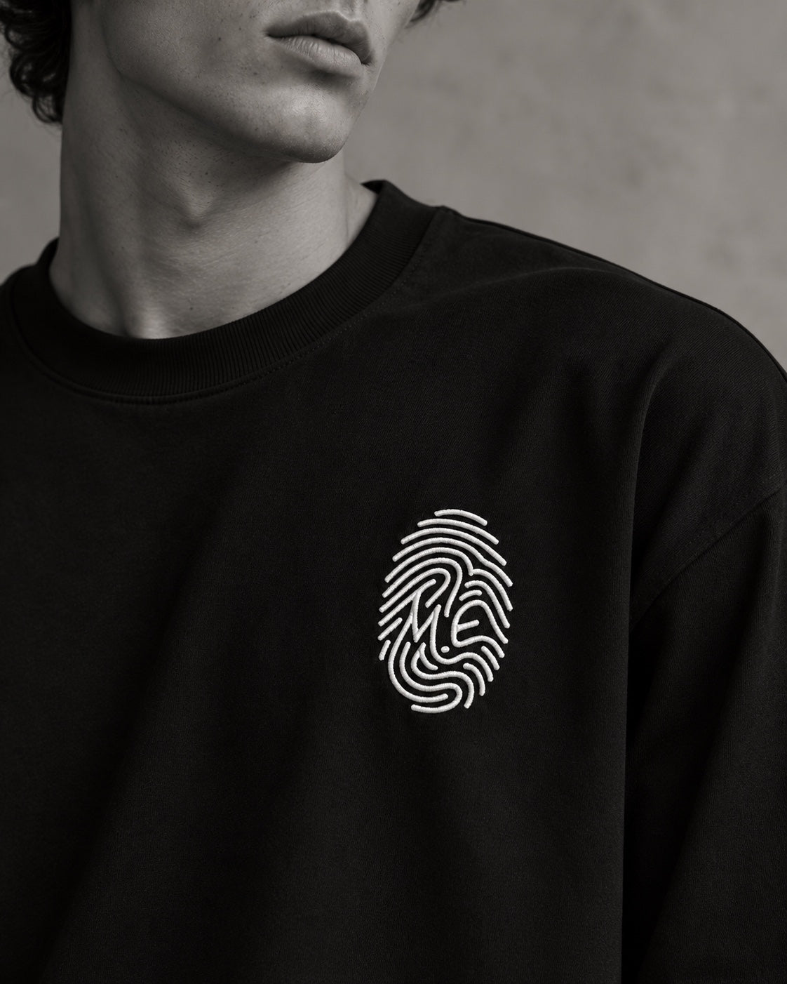 Détail de l’empreinte M.E blanche brodée — t-shirt L’Empreinte noir