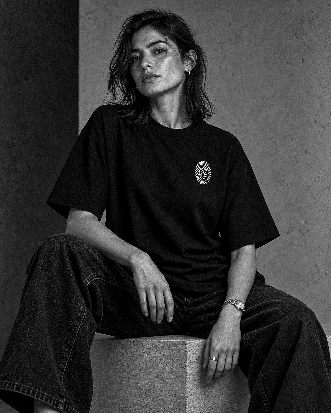 L’Empreinte — t-shirt oversize noir porté par une femme assise, vue de face